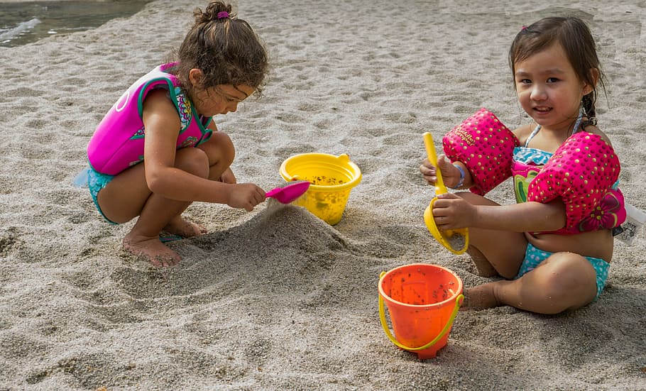 two toddler girls sitting on sand while playing during daytime HD wallpaper