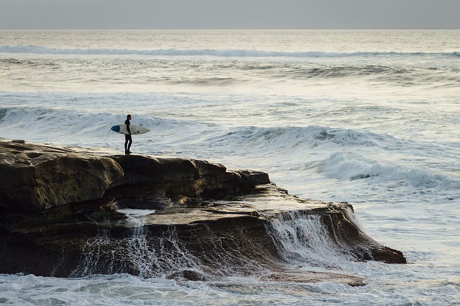 person carrying surfboard standing near seashore, person standing in island holding white surfboard HD wallpaper