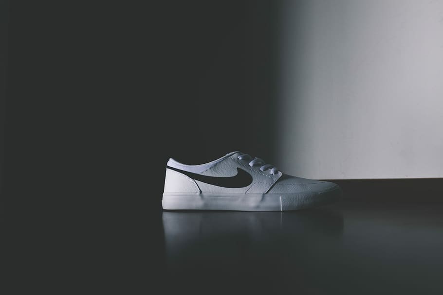 unpaired white Nike low-top shoe, unpaired white and black Nike shoe on top black surface photo