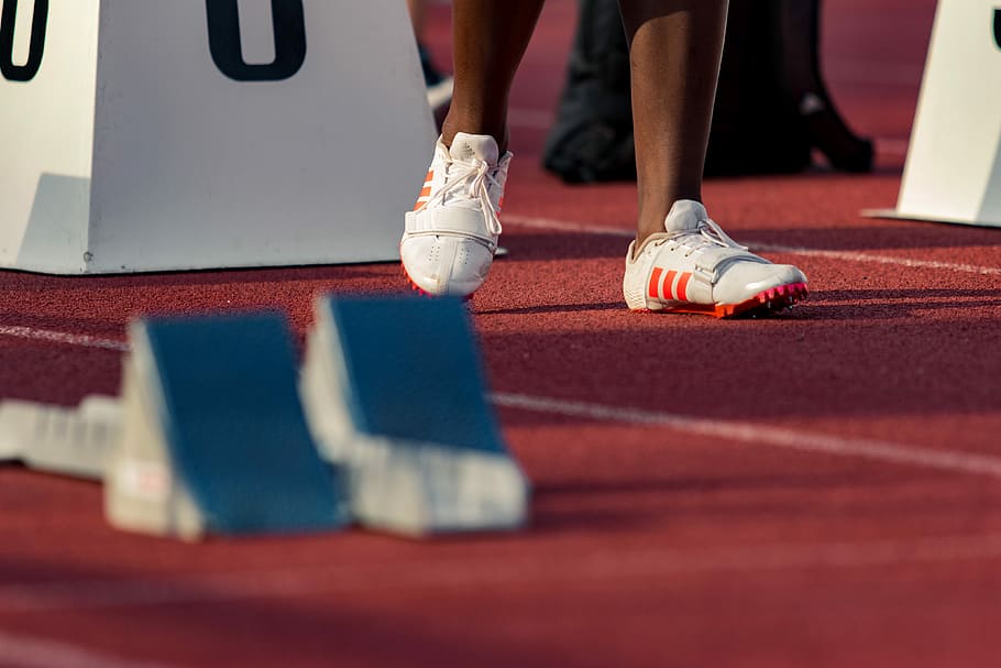 person standing beside white stand, person wearing white-and-orange adidas running shoes on track and field HD wallpaper