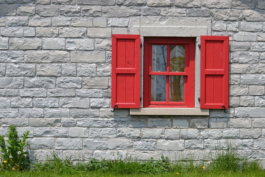 red wooden frame glass center window surrounded by grey concrete wall