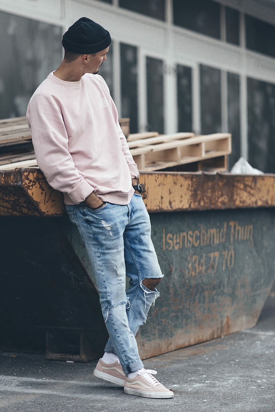 man leaning backwards on grey and white metal frame, man leaning on orange metal container near building HD wallpaper