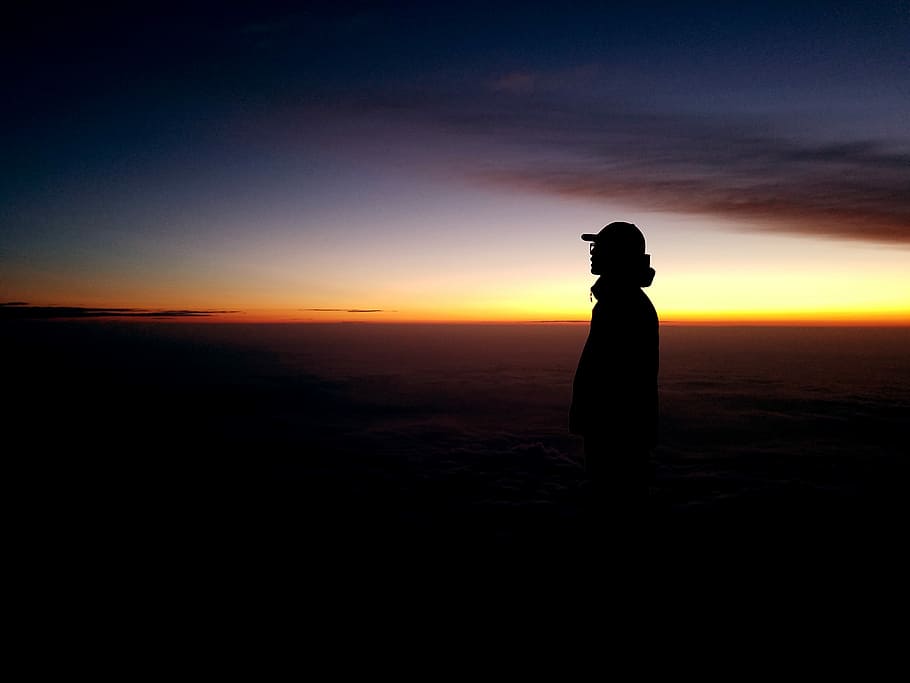 Braving the Dark, silhouette of person standing during golden hour HD wallpaper