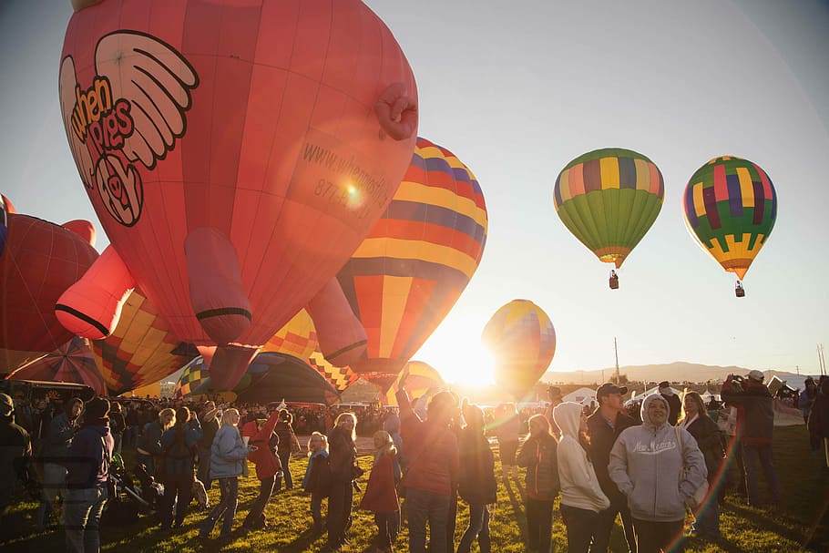 people near assorted-color hot air balloon during sunset, people standing near hot air balloons