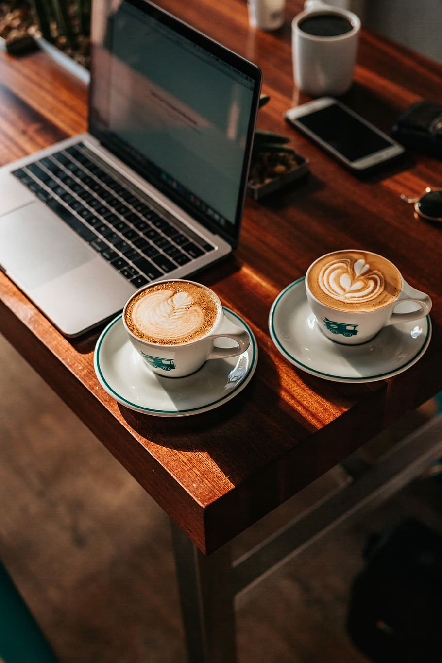 two white ceramic teacups near gray laptop computer, two cappuccino beside MacBook placed on table HD wallpaper