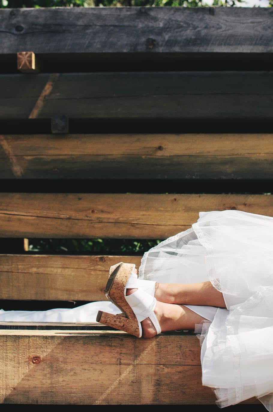 woman in white wedding dress and cork stilettos lying on wooden bench HD wallpaper