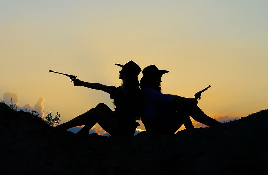 silhouette of two cowgirl holding pistols, evening, sunset, girls