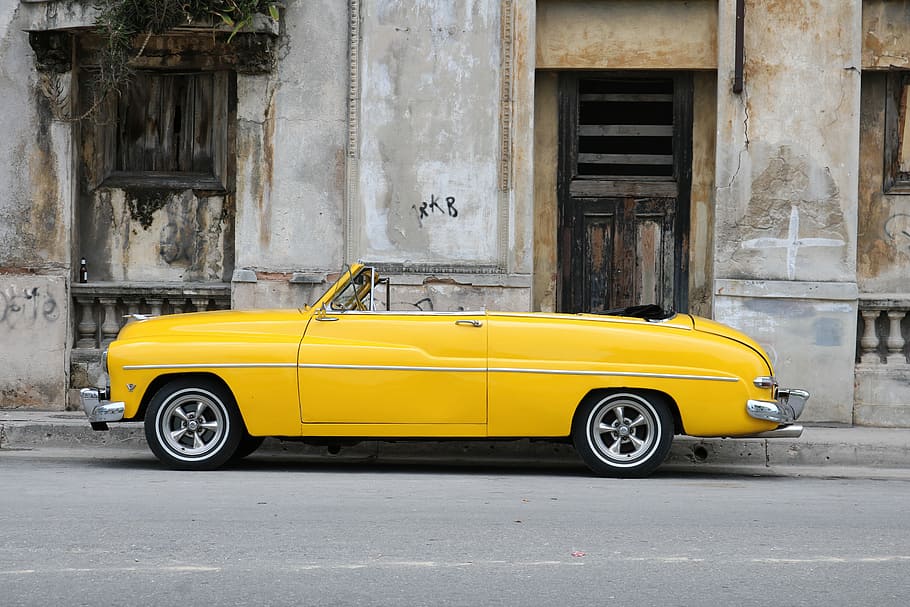 parked vintage classic car near concrete wall, yellow convertible parked near building HD wallpaper