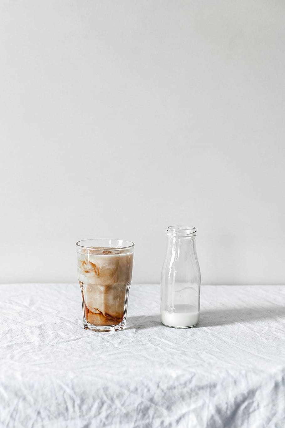 white beverage filled clear glass bottle beside brown liquid filled clear pint glass, two glasses filled with beverages HD wallpaper