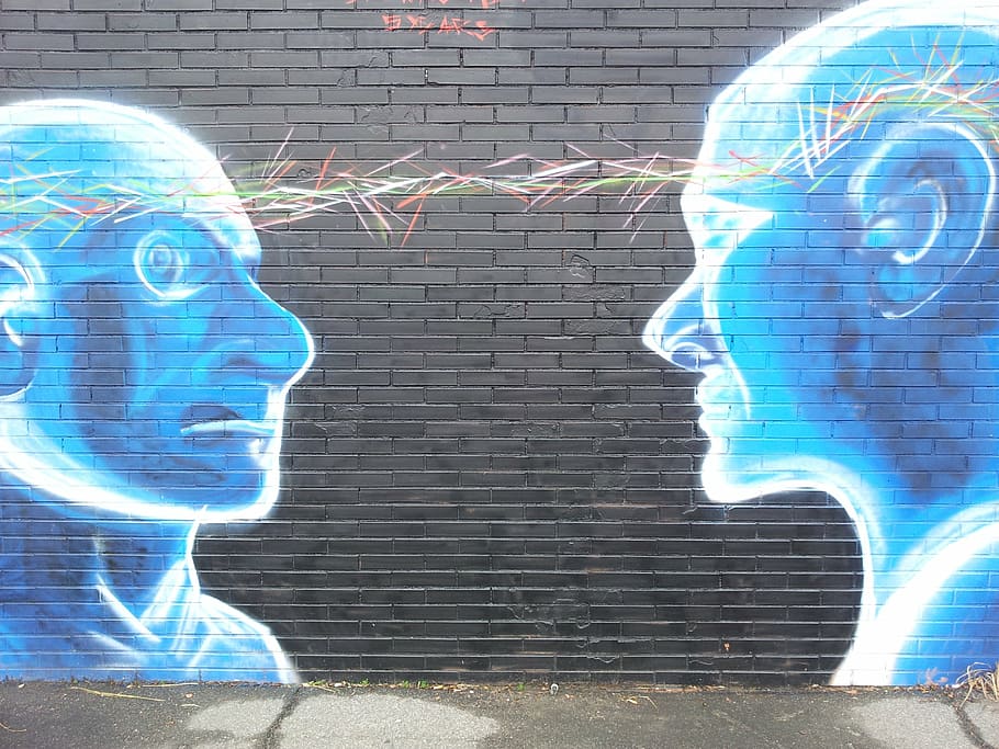 mural of two blue people with linked head on black wall, painted