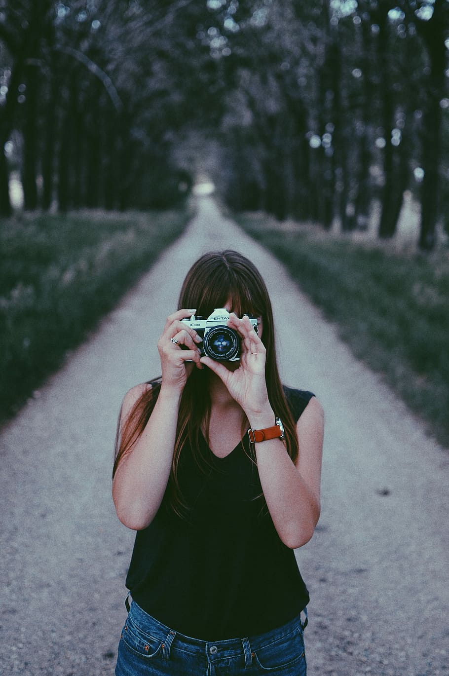 woman in black sleeveless top holding grey bridge camera at daytime HD wallpaper