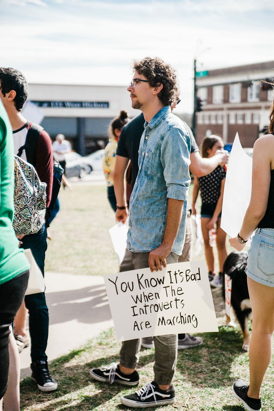 man wearing blue denim button-up shirt holding white printer paper, man holding card you know it's bad when the introverts are marching, HD wallpaper