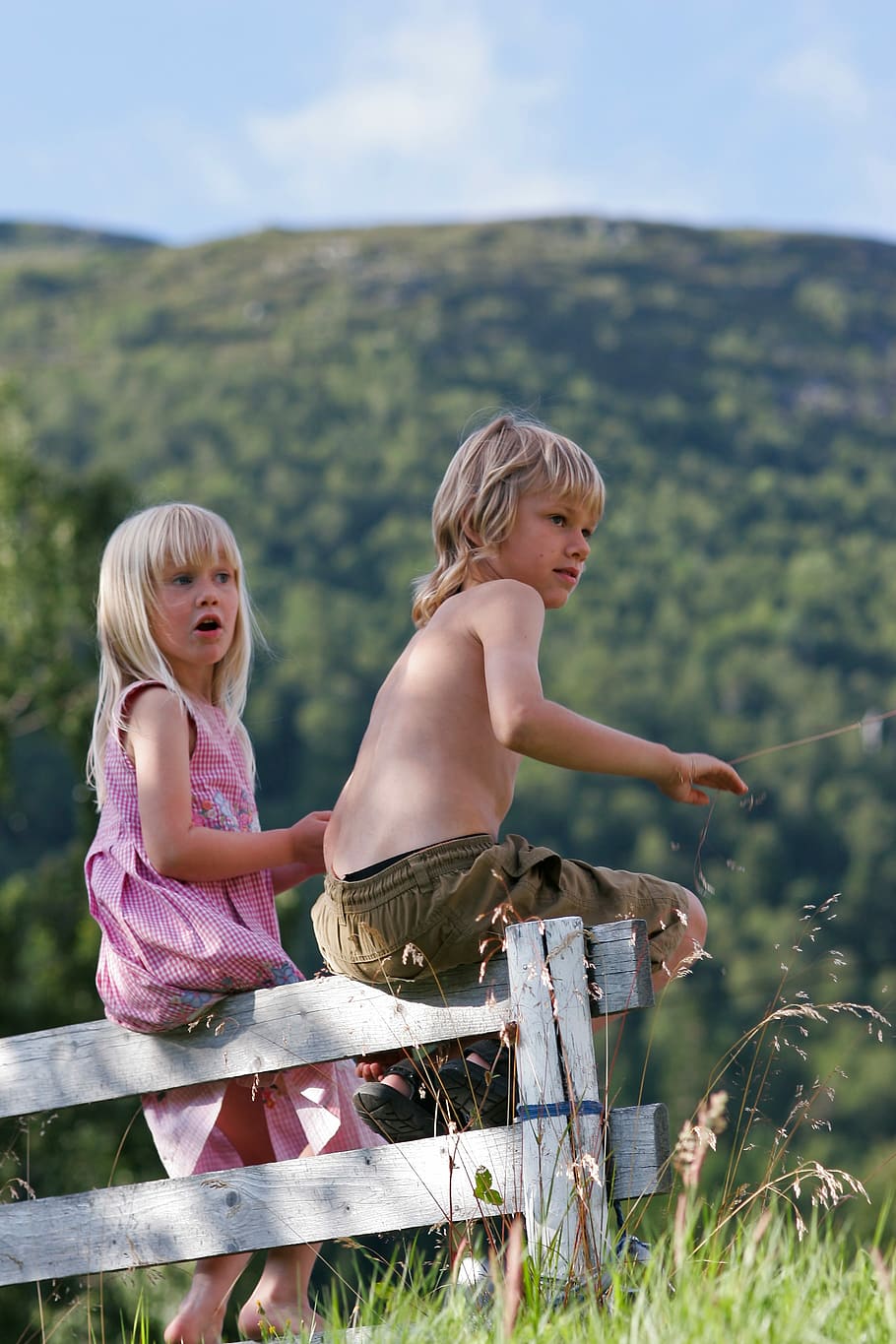 boy and girl sitting on white wooden fence near mountains, outdoors HD wallpaper