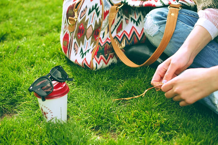 person sitting on grass near bag and cup at daytime, person sitting on green grass HD wallpaper