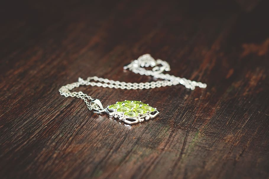 silver-colored green gemstone necklace on brown wooden board HD wallpaper