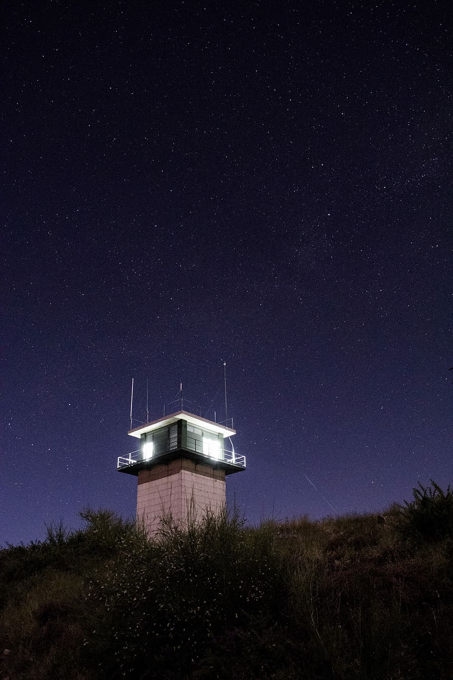 lighted guard house on mountain's peak during night time, white tower post during nighttime HD wallpaper