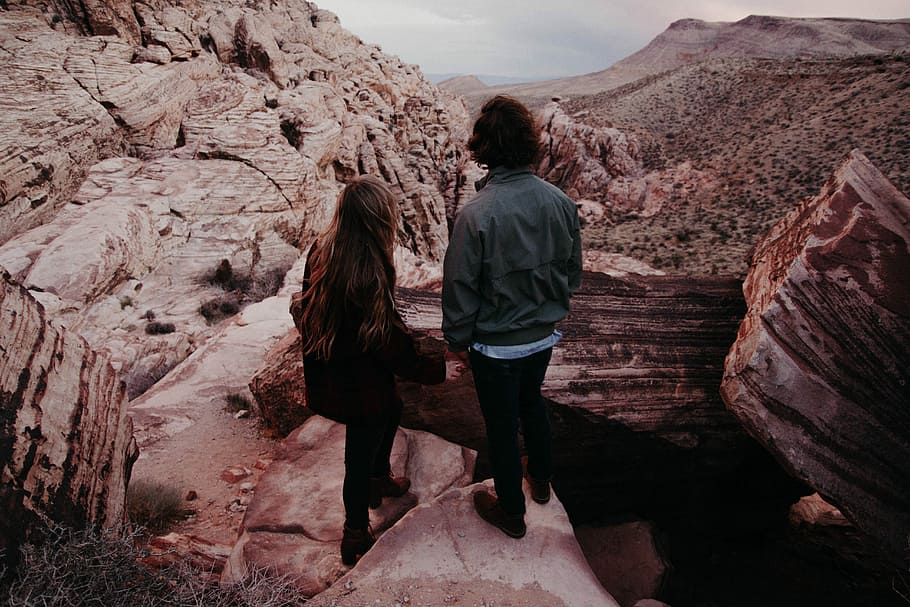 man and woman standing on hill in front of hills during daytime, man and woman standing beside each other on a canyon HD wallpaper