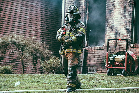 fireman holding his hand, firefighter walking away from building while adjusting gloves during daytime HD wallpaper