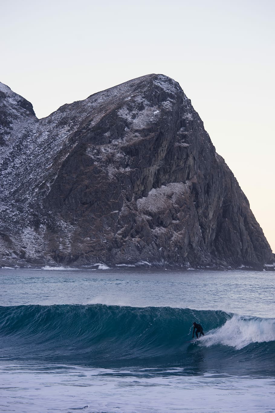 person surfing on sea near mountain, man surfing in sea near rock formation HD wallpaper