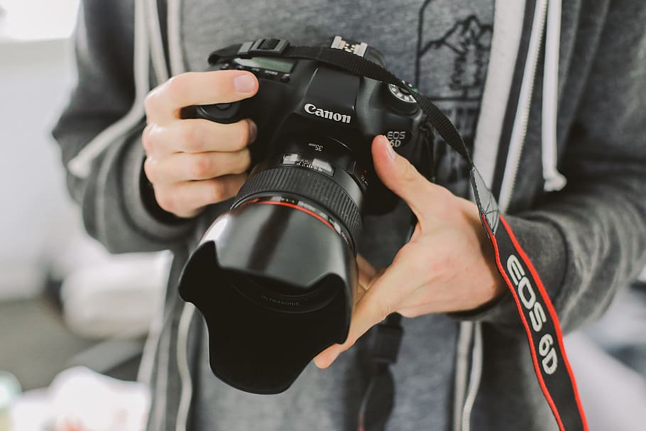 person holding Canon EOS 6D, person in gray top holding black Canon EOS camera