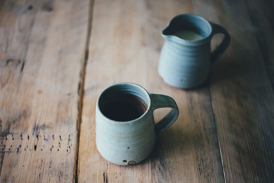 white ceramic mug with brown and white liquid inside on brown wooden surface, two gray cups on brown wooden table HD wallpaper