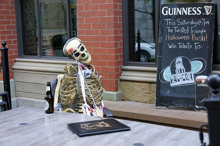 skeleton sitting on chair near menu board on storefront, dead