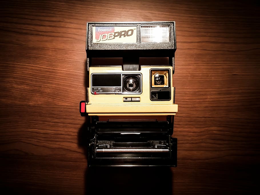 beige and black Jobpro land camera on brown wooden surface, white