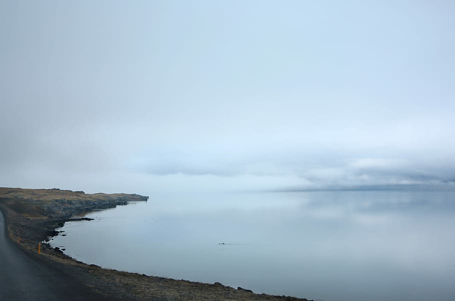 mountains near body of water, calm body of water under white sky at daytime HD wallpaper