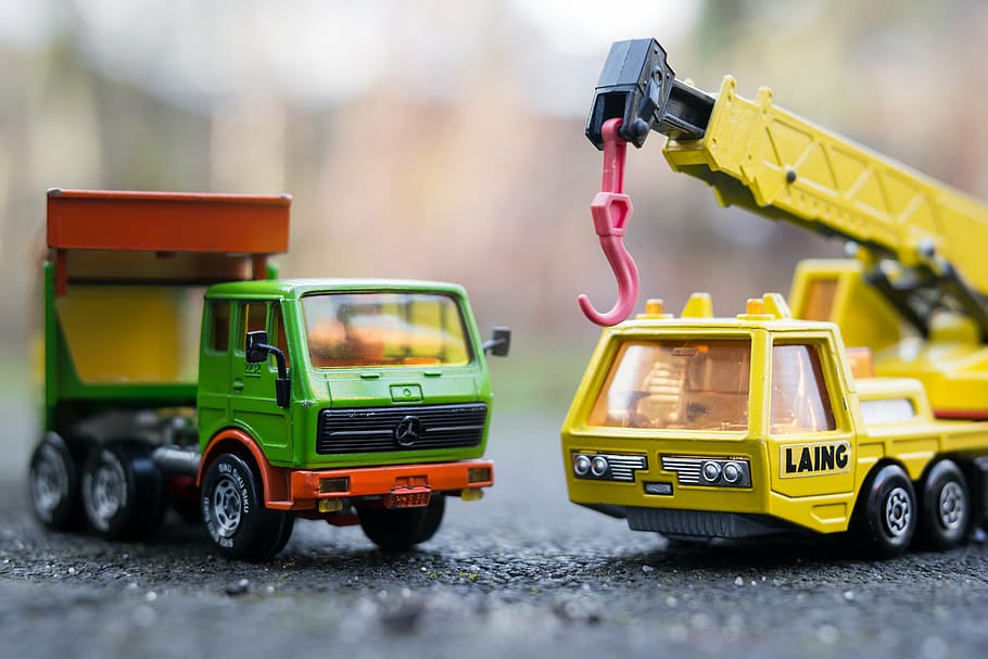 two green and yellow truck toys on gray pavement, autos, toy cars
