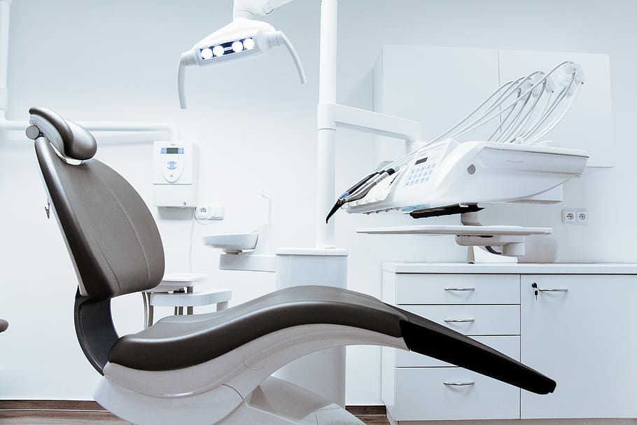 empty dentist chair, black and white medical chair beside white digital machine inside room