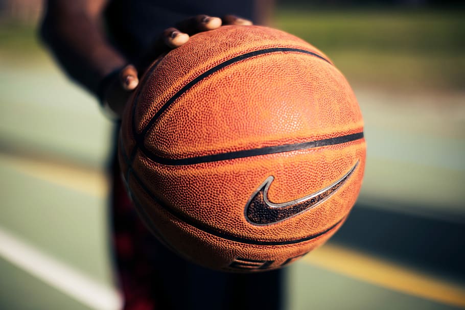 person holding brown Nike basketball, person holding Nike basketball