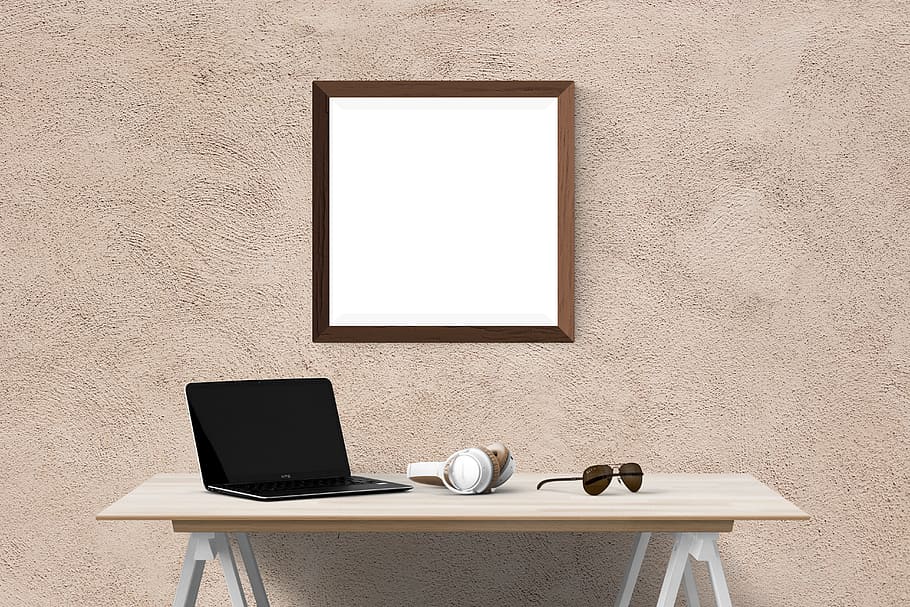 wall mirror over laptop, headphones, and eyeglasses on table