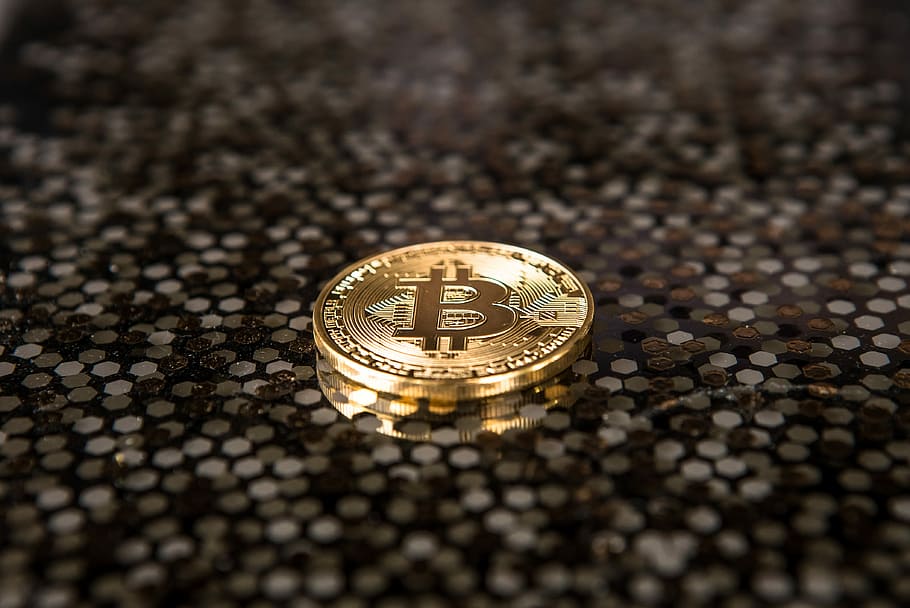 gold-colored Bitcoin coin on ground, closeup photo of Bit coin
