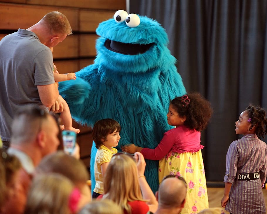 children standing around Cookie Monster mascot, muppet, sesame street