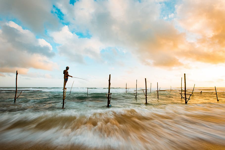 time lapse photo of kid fishing on seashore during daytime HD wallpaper