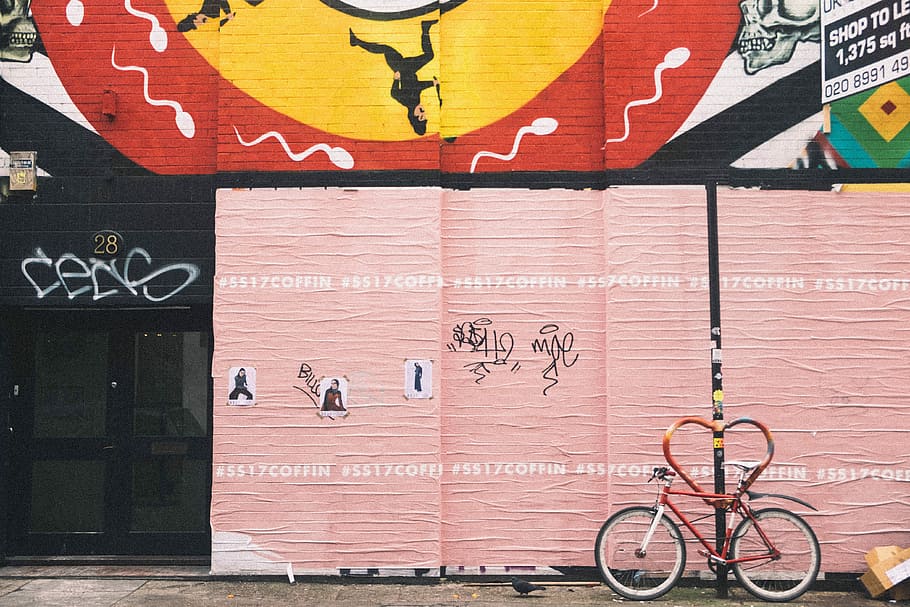 red bicycle near pink wall, red and white bicycle beside beige painted wall