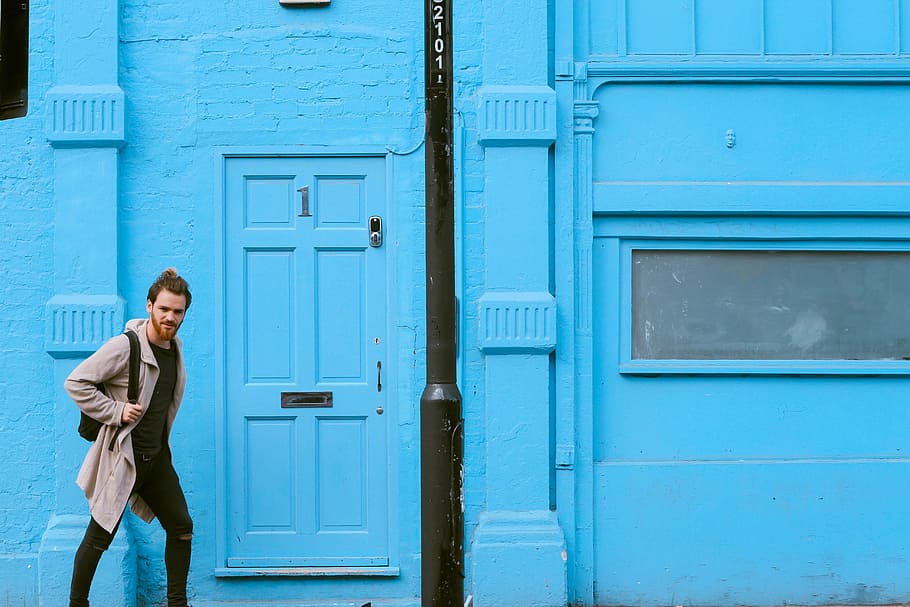 man with backpack walking beside blue building, people, wall HD wallpaper