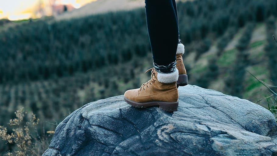selective focus photography of person standing on rock, person standing on rock at daytime HD wallpaper