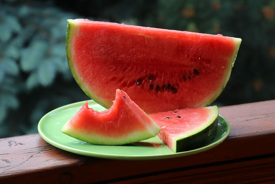 person showing sliced watermelons on green ceramic plate, sectioned HD wallpaper