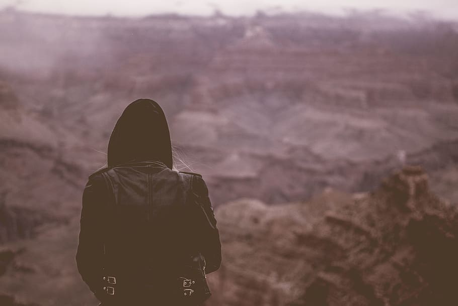person wearing black hoodie standing at cliff, selective focus photography person in black hoodie on top of mountain HD wallpaper