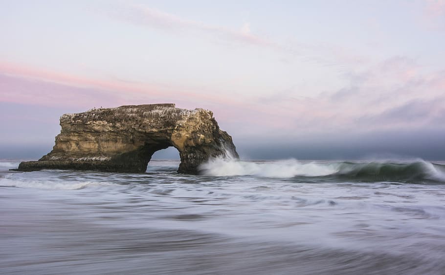 brown rock formation on sea, brown arch on ocean at daytime, wave HD wallpaper