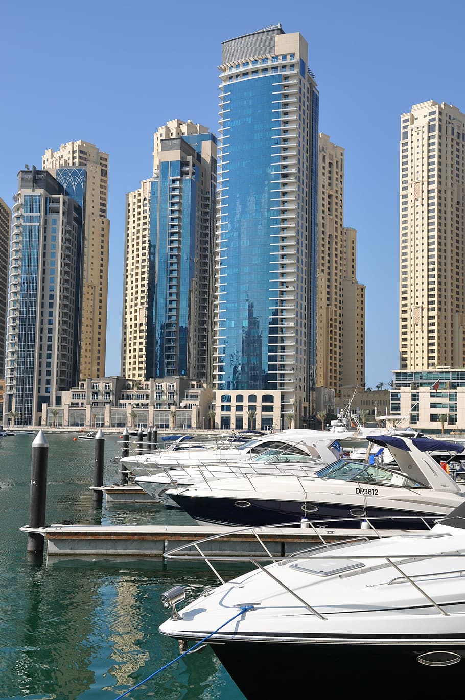bowrider boats beside docks and buildings at distance, dubai