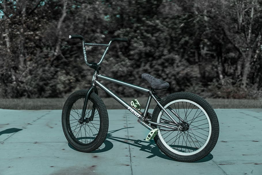 grayscale photo of BMX bike on concrete pavement, gray BMX bike outdoors during daytime