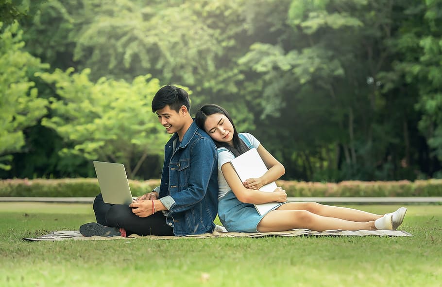 couples sitting on green brown textile on green grass field, fatigued