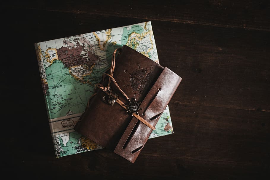 wallet on top of map, brown leather pouch on teal and white map
