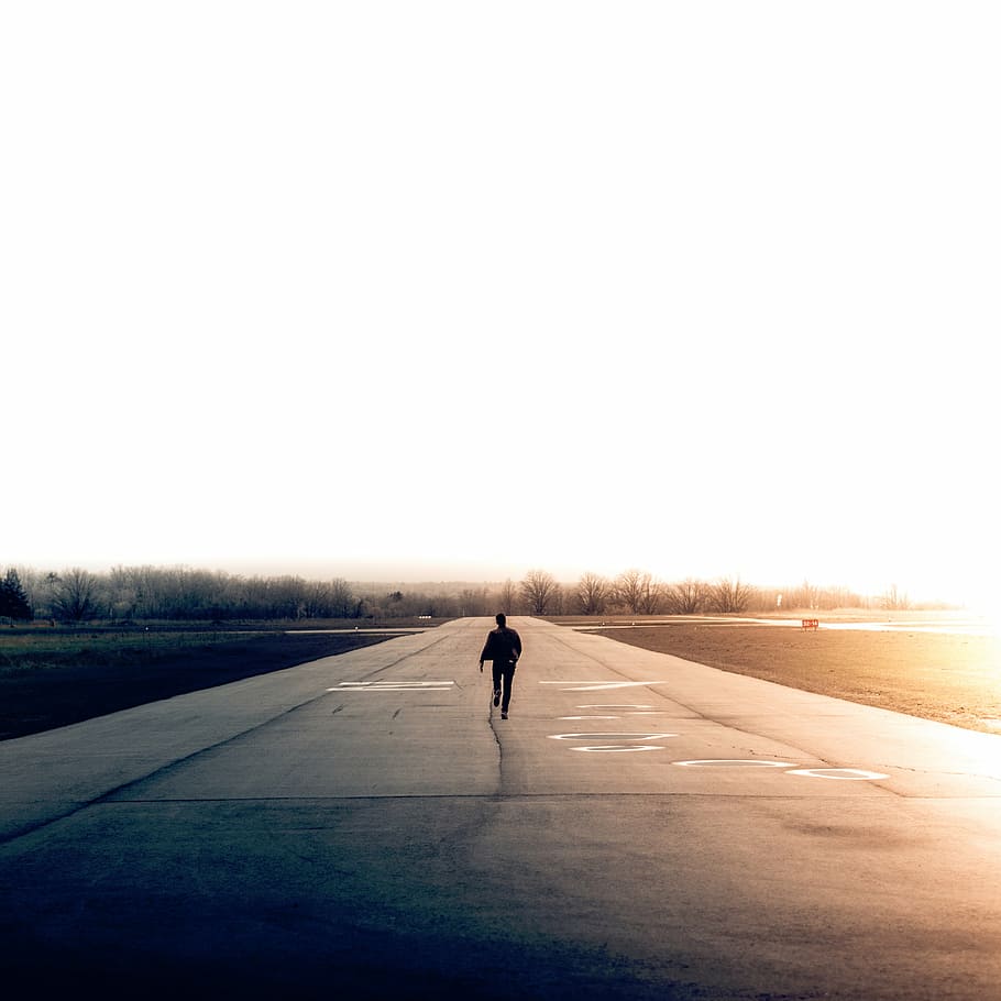 man standing on gray asphalt road near trees during daytime HD wallpaper