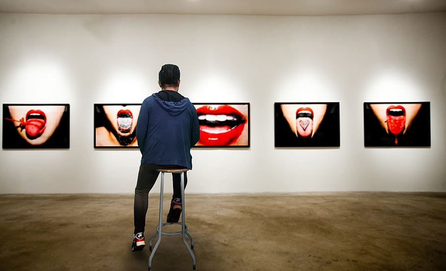person wearing blue hoodie sitting in brown wooden stool in front of lips photo gallery HD wallpaper