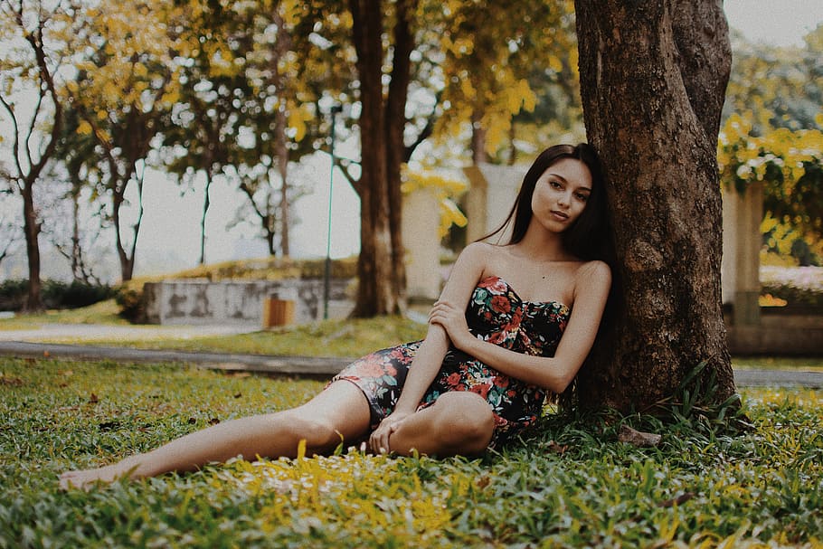 woman leaning on tree during daytime, woman leaning of tree wearing black and pink floral mini dress at daytime HD wallpaper