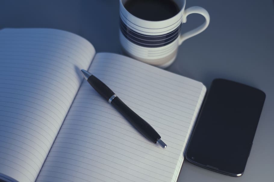 clear black-lined white notebook near pen and coffee mug, in the workplace HD wallpaper