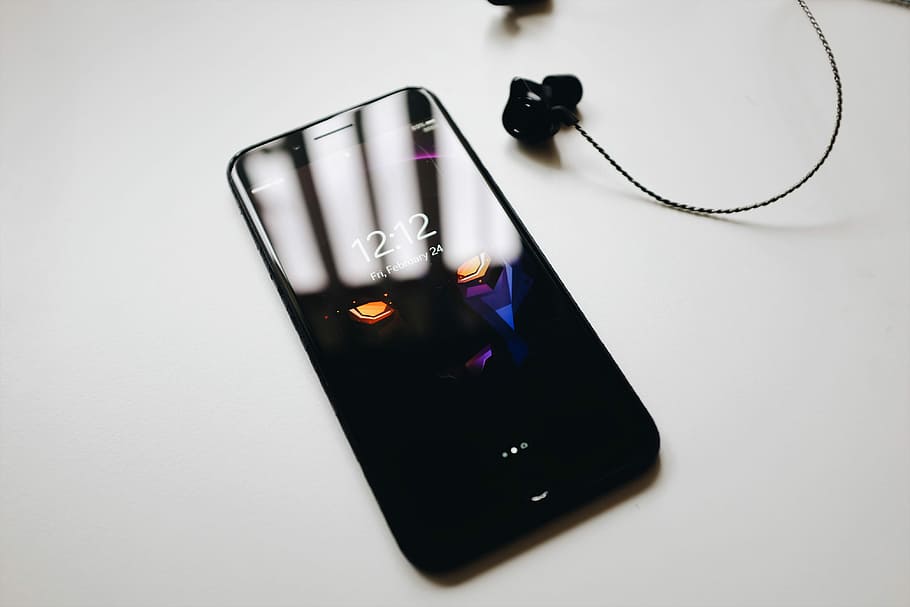 post-2017 iPhone, black smartphone turned on beside black earbuds HD wallpaper